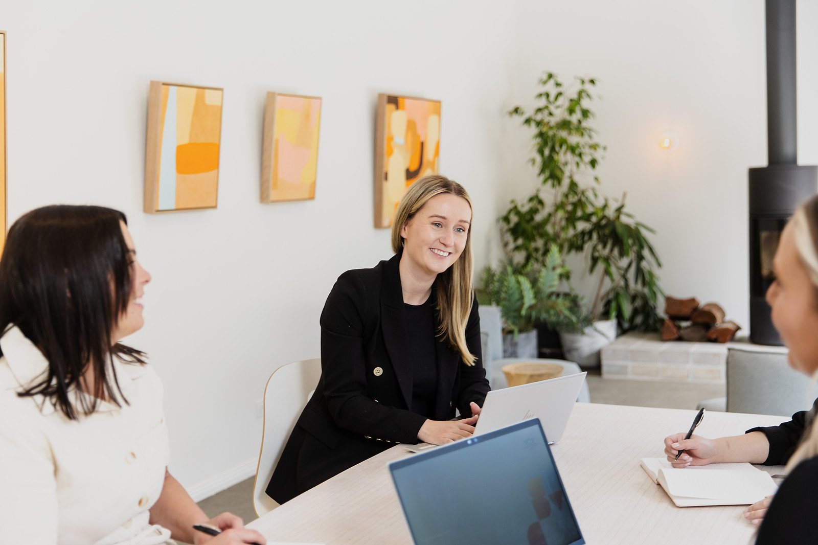 A team working at a table on laptops, smiling and chatting.