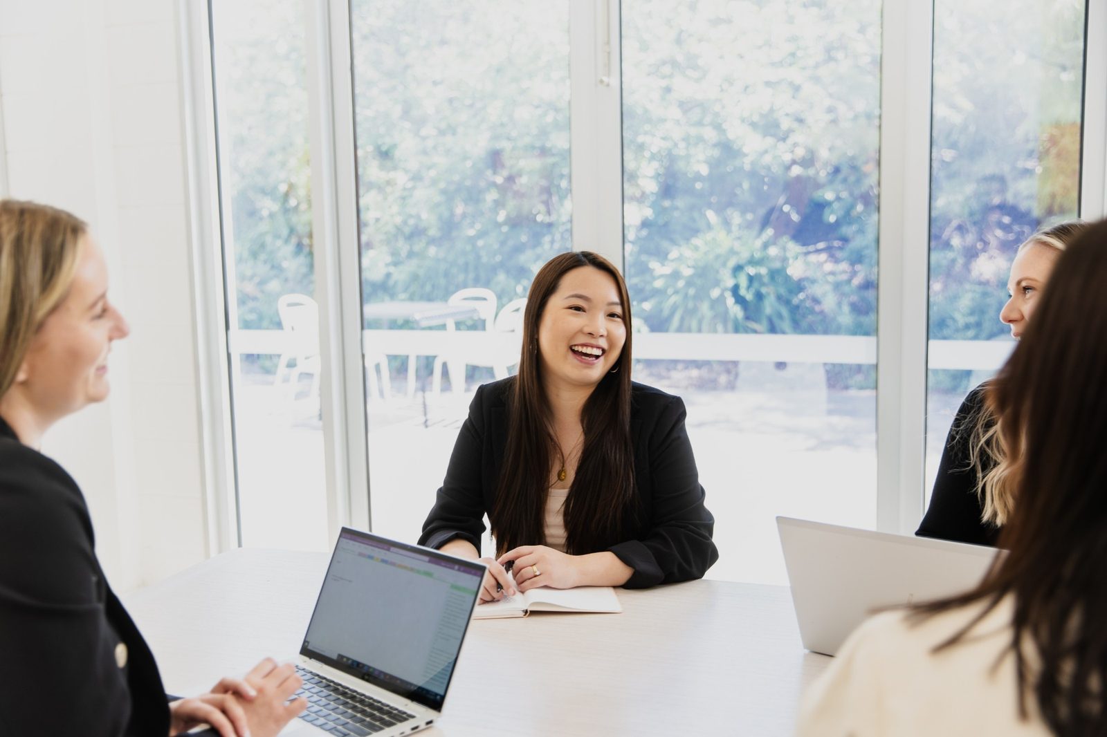 A smiling woman laughing with colleagues around a meeting table